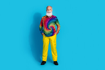 Full size photo of funky old man posing model hands pockets dressed colorful disco outfit isolated on blue color background