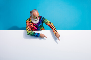 Photo of eccentric funky aged man direct fingers empty space placard wear shirt isolated on blue color background