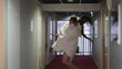 © ekaterinabyuksel - Happy loving couple having fun in a dark hotel corridor, wrapped in white blankets. A beautiful wife and a handsome husband are enjoying a tender moment spent together. A man carries a woman on his