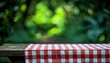 © Rangga Bimantara - A rustic wooden table adorned with a red and white checkered cloth, set against a lush, green background, suggesting a picnic atmosphere.