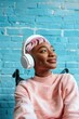 © vefimov - A young woman with pink hair listening to music on her headphones, sitting in a modern and colorful room.