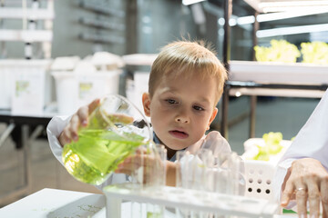 Little child boy scientists learning science and doing analysis with glassware, liquid and tube in laboratory. Scientific experiment and Research. Early development of children