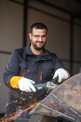 Metal worker using angle grinder creating sparks in workshop