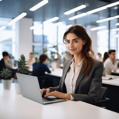 Poster - Professional woman working on laptop in modern office environment with colleagues in background