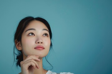 attractive asian woman thinking isolated on blue background