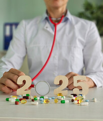 A healthcare in a white coat examines various pills and supplements arranged around the year 2025