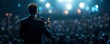 © Cheewynn - Keynote speaker in suit, microphone in hand, stage spotlight, engaging with audience, dynamic lighting, inspirational speech scene, business event