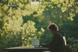 © Vasili - Young man in a park sitting with a laptop, working intently in a natural setting with lush green surroundings. Concept of remote work and connection with nature.
