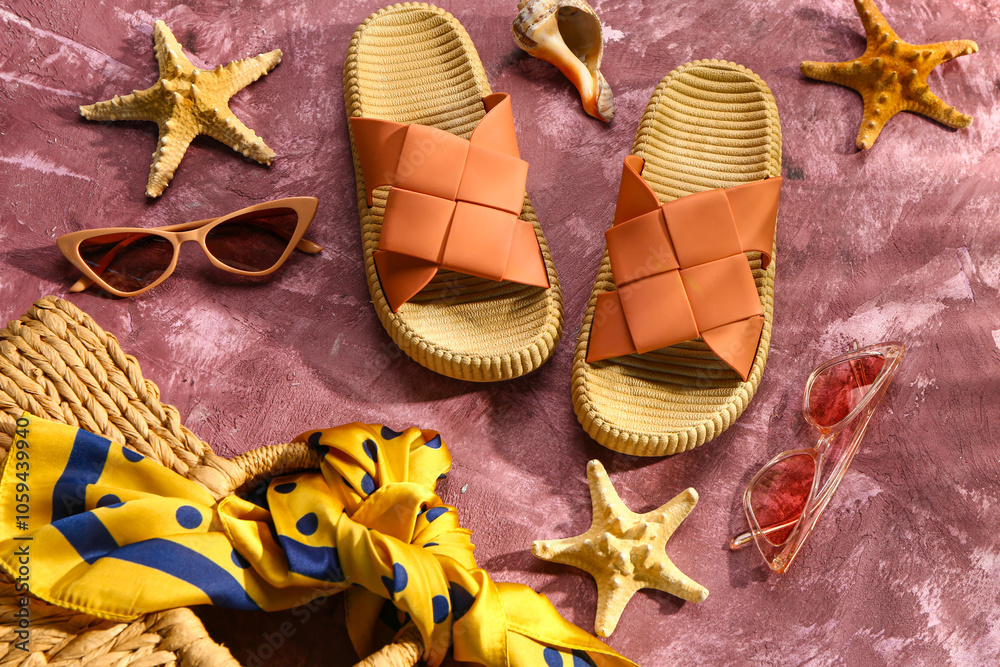 Female stylish flip flops with beach accessories on grunge pink background