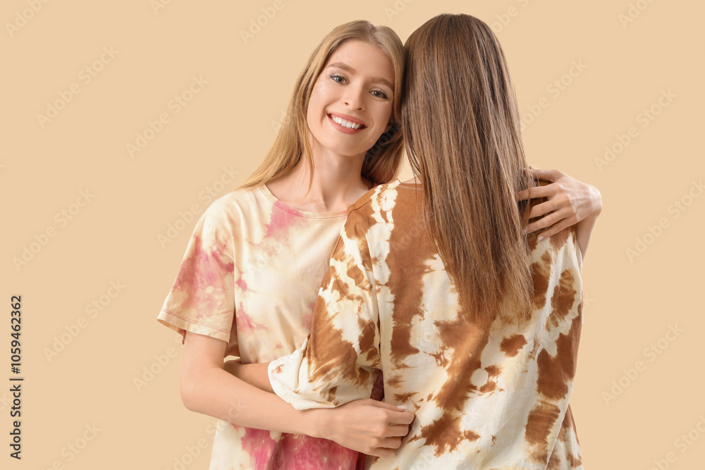 Young women hugging on beige background