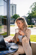© DZ FILM/Stocksy - A woman uses a laptop sitting on a cafe terrace