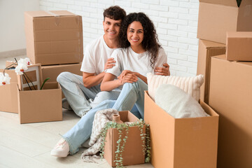 Young happy couple sitting on floor near cardboard boxes in their new flat