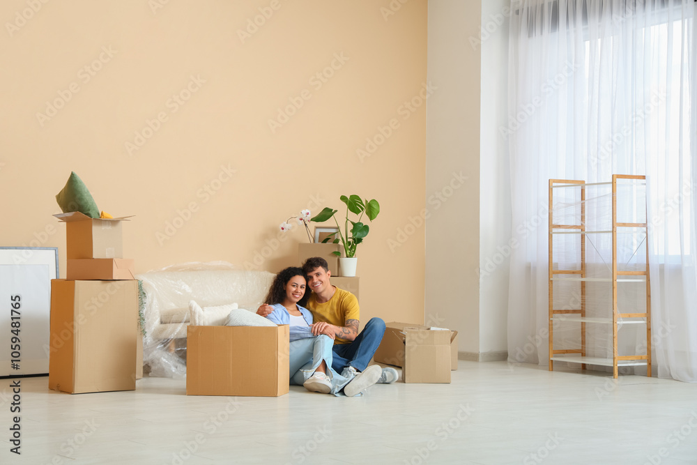 Young couple sitting near cardboard boxes and packed sofa in their new flat