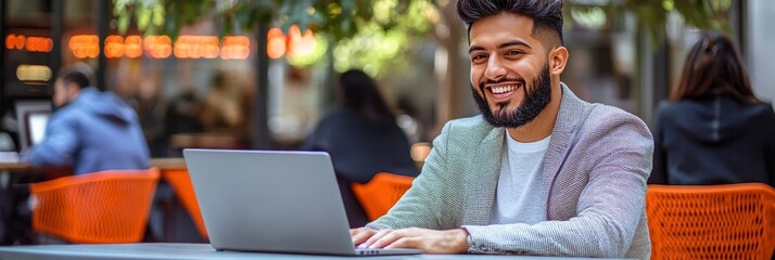 Poster - Smiling Young Professional Working on Laptop in Outdoor Cafe, Enjoying Remote Work Lifestyle