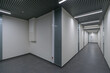 © alhim - A long corridor with white walls, gray floor tiles and glass doors.