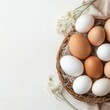 © nattapon - A beautiful arrangement of brown and white eggs in a rustic wicker basket accompanied by delicate flowers, perfect for culinary blogs, Easter themes, or food-related marketing materials,