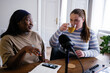 © Oleksii Syrotkin/Stocksy - Plus size woman drinking tea while recording podcast with friend