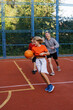© Oleksii Syrotkin/Stocksy - Kids playing basketball with father on outdoor court in park