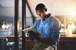 © peopleimages.com - Night, tablet and black man in office for business, connectivity and research for webdesign. Programmer, schedule and reading on tech for software information, company website update or online review