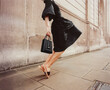 © Ulas&Merve/Stocksy - Elegant Woman in Black Dress Walking on City Sidewalk