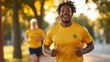 © LifeMedia - A man, smiling brightly, jogs down a sunlit path sporting a yellow t-shirt, capturing the essence of joy, health, and spirited outdoor activity.