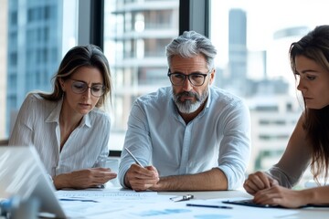 Poster - Three professionals collaborate on a project at an office table, engaged in discussion, analysis, and brainstorming over documents in an urban office setting.