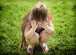 © Hulya - A little girl covering her face with her hands in a gesture of sadness or distress, capturing a candid and emotional moment outdoors.