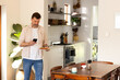 © Wavebreak Media - senior man using smartphone while holding plate of food in kitchen, at home