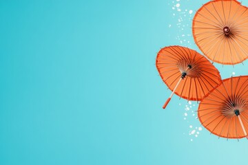 Three vibrant orange umbrellas appear to splash across a bright azure background, creating a whimsical and artistic composition full of color and playful movement.