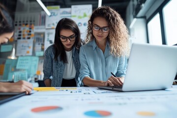 Poster - Two young women analyze charts and graphs at a workspace, reflecting teamwork and collaboration in a modern business environment.