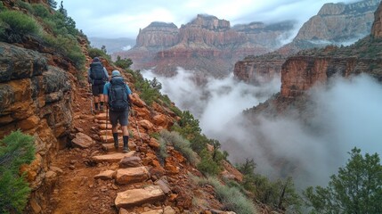 Poster - Two hikers trek along a narrow path carved into the rocky landscape, surrounded by dramatic cliffs and swirling mist in a serene national park setting.