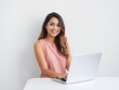 © Chalermrach - Happy young woman with a bright smile, looking stylish as she poses with a laptop against a white background, beautiful, white wall, posing