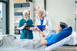 © NanSan - Two Muslim female doctors check the medical history and symptoms of a male patient lying in bed after surgery at the hospital, monitoring his recovery and health status