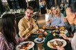 © Mediteraneo - Group of happy friends eating lunch together in a restaurant. They eat delicious salads and hamburgers.
