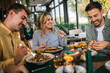 © Mediteraneo - Group of happy friends eating lunch together in a restaurant. They eat delicious salads and hamburgers.