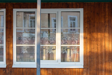 Wall Mural - A window with a floral patterned curtain is reflected in the window of a buildin