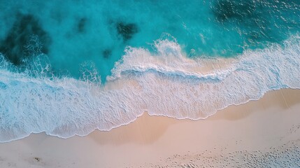  An aerial view of white sandy beach with turquoise ocean waves crashing on the shore.
