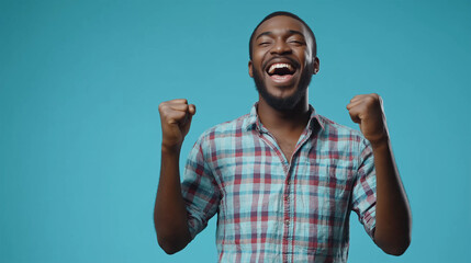 Expressive african american man celebrating success raising his fists up on blue background