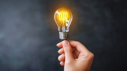 Hand holding glowing light bulb on dark background. Concept of creativity, innovation, and new ideas.