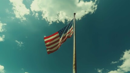 Large American flag glowing from backlight from the sun, against cloudy sky
