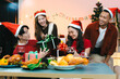 © NINENII - Dinner and group of people celebrating together at Merry Christmas & Happy New Year. Friends are happy and celebrating with food, wine and friendship of love and gift exchange at the event.