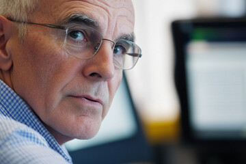 Poster - Older man gazes thoughtfully at computer screen in office