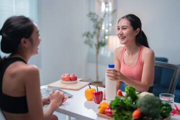 Two women are sitting at a table with a laptop, milk bottle, fruits and vegetables, discussing healthy eating habits, during an online consultation with a nutritionist