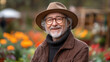 © sommersby - An elderly gentleman with glasses and a hat beams joyfully while standing in a vibrant garden filled with blooming flowers during spring
