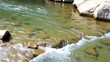 © PuriStudio - Crystal clear water flowing gently over smooth river rocks in a serene natural setting, natural, environment