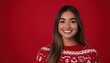 © Anastasiia - Smiling woman wearing an ugly Christmas sweater against a vibrant red background