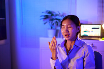 Asian woman diligently works overtime, managing a heavy workload with focus and determination. Despite the challenges, her commitment shines through as she strives  and meets her deadlines.