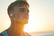 © Vii - A young man wearing earphones stands on the beach, enjoying his music