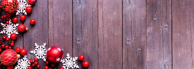 Poster - Christmas corner border of red  baubles, snowflakes and berries. Above view on a dark wood background. Copy space.