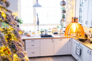 Wall Mural - Christmas decor in white kitchen, modern rustic interior with a snowy Christmas tree and gold fairy lights. New Year, Christmas mood, cozy home. 